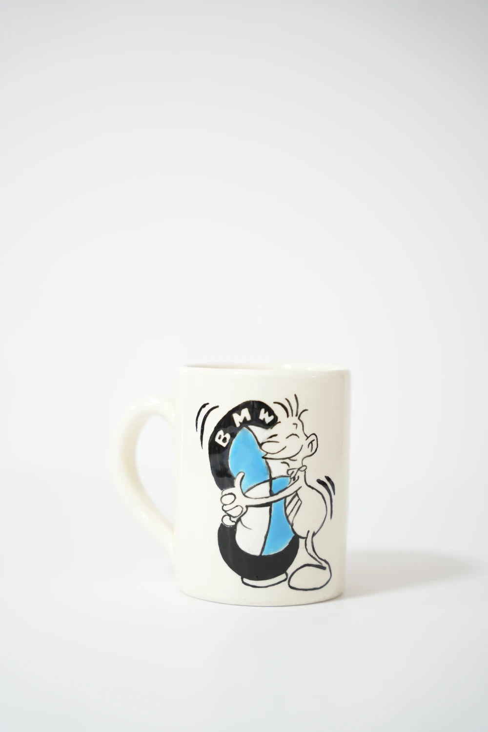 فنجان سيراميك أبيض مكتوب عليه بخط عربي أسود الجملة: "ركّز عالمال والسيّارات أكثر من البشر، عمرك شفت بي أم خاينة أو دولار حقير؟!".